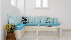 Una sala de estar moderna con un sofá azul, almohadas a rayas, una mesa de centro blanca y un florero de mimbre con flores.