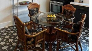A kitchen with a round glass table, four wicker chairs, a ceiling fan, and a black stove.