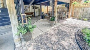 A covered patio area with outdoor furniture, a wooden deck, and a thatched roof structure.