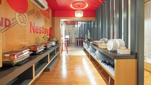 Ein Nestlay Hotel-Korridor mit Holzboden, roter Decke und einer Büffet-Ecke mit Speisebehältern.