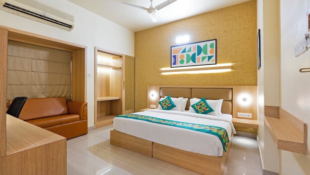A hotel room with a bed, a sofa, a wardrobe, and a ceiling fan. - Treebo Premium Nestlay Rooms Nungambakkam (Chennai)