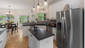 Een moderne keuken met witte kasten, een roestvrijstalen koelkast en hanglampen.