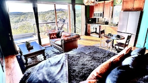 Un dormitorio con una cama grande, vistas al exterior, una kitchenette y un comedor.