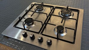 A kitchen with a four-burner gas stove, a sink, and a countertop.
