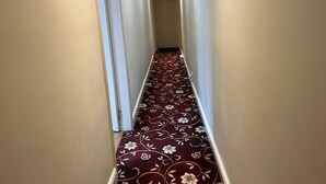 A narrow hallway with a patterned carpet and white walls.
