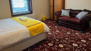 A bedroom with a bed, a wardrobe, a sofa, and a large mirror.