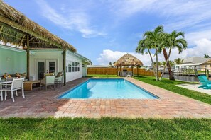 Um quintal com piscina, varanda coberta e cerca de madeira.