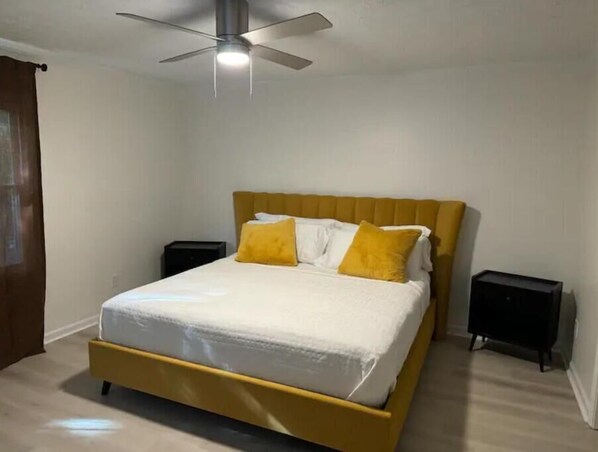 Une chambre à coucher avec un lit, un ventilateur de plafond et deux tables de chevet.