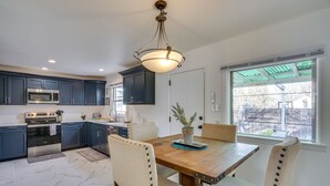 Una cucina moderna con mobili blu scuro, elettrodomestici in acciaio inossidabile e un tavolo da pranzo in legno con sedie.