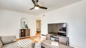 Un soggiorno moderno con un divano, un tavolino, una TV e una ventola a soffitto.