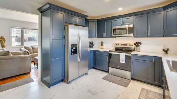 Una cucina moderna con mobili blu scuro, elettrodomestici in acciaio inossidabile e pavimento in marmo.