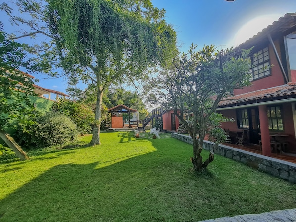 Un jardín bien cuidado con un pabellón, muros de piedra y un cielo despejado.