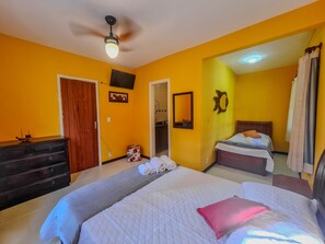 A hotel room with two beds, a ceiling fan, a TV, and a bathroom visible through an open door. - Casa em Geribá (Manguinhos Armação dos Búzios)