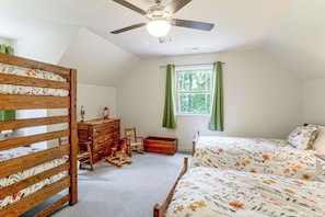 Un dormitorio con cama, cómoda, mecedora y ventana con cortinas.