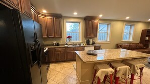 A kitchen with wooden cabinets, a granite countertop, and a black refrigerator. - North Hill Section Home; walk to UVMMC & UVM, Chabad, downtown, lake. (Burlington)
