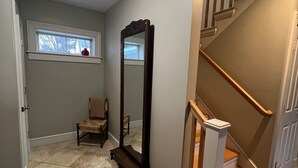 A hallway with a wooden staircase, a large mirror, and a chair. - North Hill Section Home; walk to UVMMC & UVM, Chabad, downtown, lake. (Burlington)