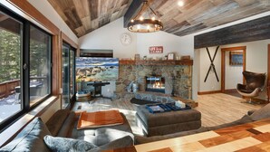Una sala de estar acogedora con chimenea de piedra, ventanas amplias y un rincón de estar confortable.