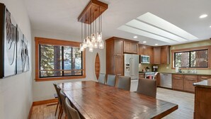 Una cocina moderna con armarios de madera, una gran mesa de comedor y un tragaluz.