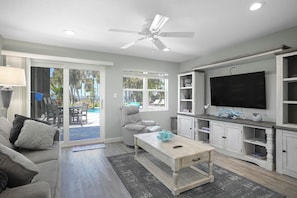 A living room with a sofa, a coffee table, a TV, and a ceiling fan.