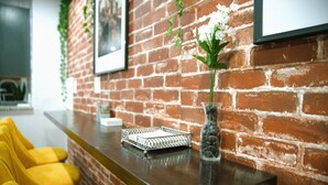 A reception area with a brick wall, a reception desk, a vase with flowers, and yellow chairs. - Serenity Suite Homes 2BD/1BA near Logan Intl/Metro (Boston)