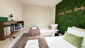 A hotel room with two beds, a bookshelf, a green wall with a sign, and a ceiling fan. - Serenity Suite Homes 2BD/1BA near Logan Intl/Metro (Boston)