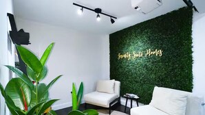 A modern living room with a green wall, white sofas, and a ceiling-mounted projector. - Serenity Suite Homes 2BD/1BA near Logan Intl/Metro (Boston)