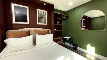 A modern bedroom with a large bed, a built-in wardrobe, a mirror, and framed pictures on the wall.