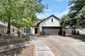 A residential property with a garage, a paved driveway, and a stone pathway leading to the entrance. - FULLY REMODELED-BEST LOCATION IN AUSTIN Pet Friendly-Gateway to the Hill Country (Austin)