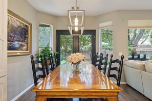 A dining room with a wooden table, chairs, a vase of flowers, and a painting on the wall. - FULLY REMODELED-BEST LOCATION IN AUSTIN Pet Friendly-Gateway to the Hill Country (Austin)