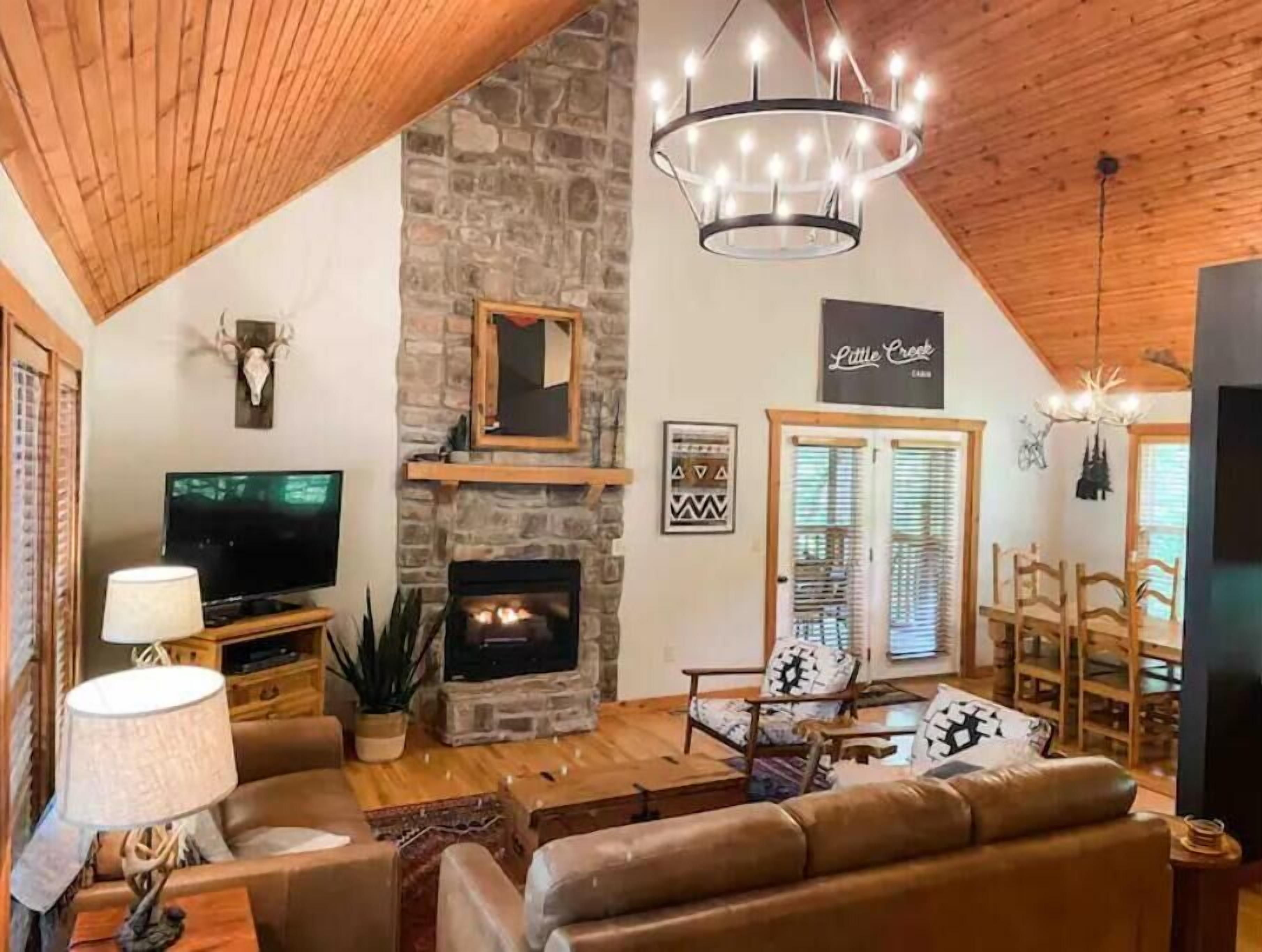 A cozy living room with a stone fireplace, a television, and comfortable seating.