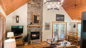 A cozy living room with a stone fireplace, a television, and comfortable seating. - Little Creek Cabin (Branson West)