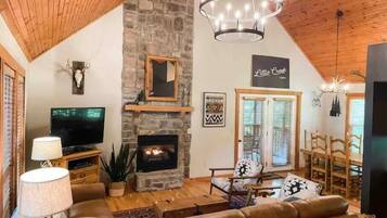 A cozy living room with a stone fireplace, a television, and comfortable seating.