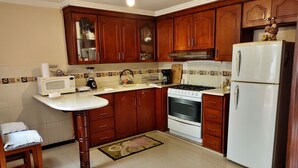 Una cocina con armarios de madera, un refrigerador blanco, una estufa y un microondas.