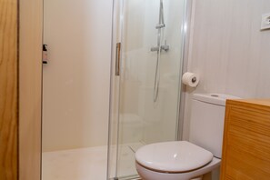 A bathroom with a glass shower enclosure, a toilet, and a wooden cabinet. - Alfacs Village (Alcanar)