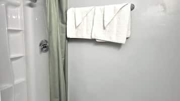 A bathroom with a white door, a shower, and a towel rack with two towels.
