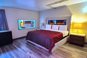 A modern hotel room with a bed, bedside tables, a TV, and a fireplace. - Elite Inn & Suites South Holland Chicago (South Holland)