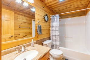 Ein Badezimmer einer Holzhütte mit Waschbecken, Toilette und Badewanne.