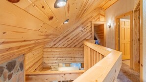 Un intérieur en bois avec un plafond en pente, un mur en pierre et un escalier en bois.