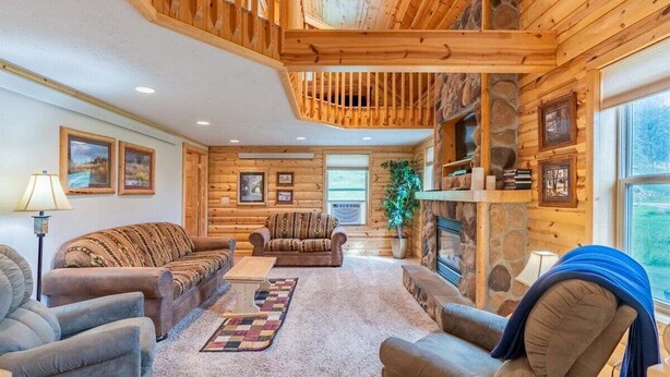 L’intérieur d’une cabane en rondins, avec une cheminée, des murs en bois et un coin salon confortable.