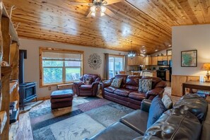 A cozy living room with a fireplace, leather sofas, and a wooden ceiling.