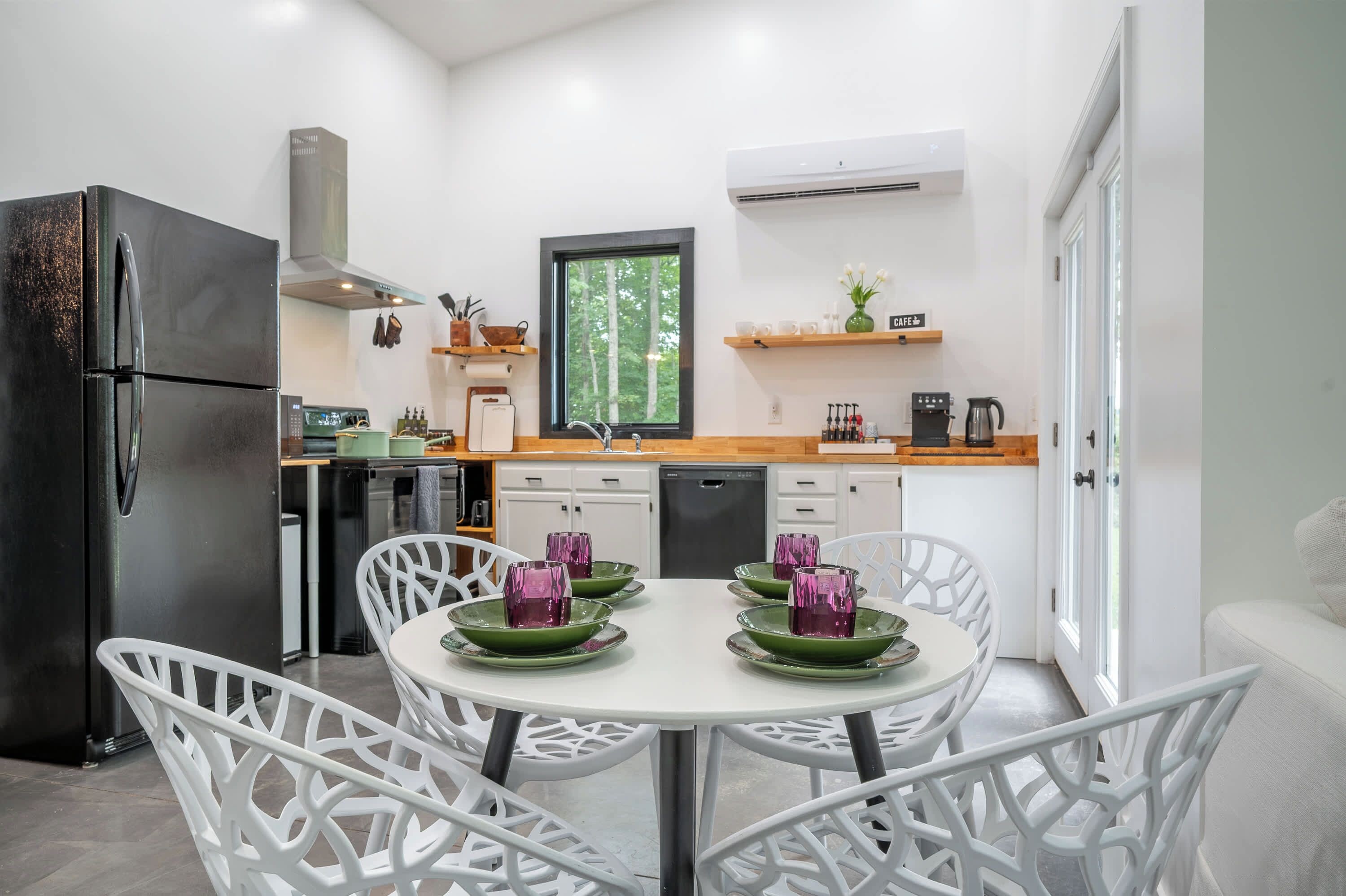 Una cocina moderna con horno integrado, refrigerador y ventana con vista a un bosque.