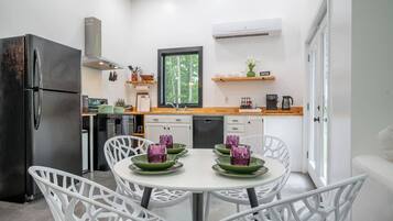Una cocina moderna con horno integrado, refrigerador y ventana con vista a un bosque.