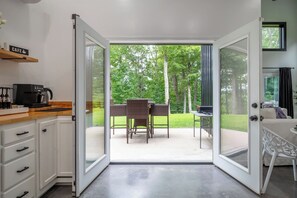 Huone, jossa on keittotila, ruokapöytä tuoleineen ja näkymä vehreälle ulkoalueelle.
