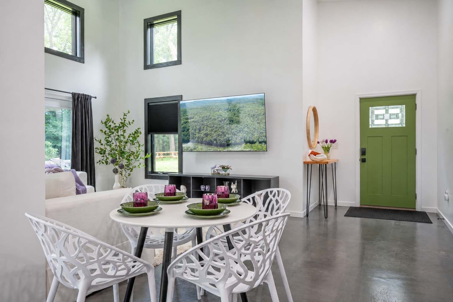 A dining area with a round table, white chairs, and a flat-screen TV mounted on the wall.