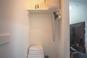A bathroom with a towel rack, a towel, and a shower area.