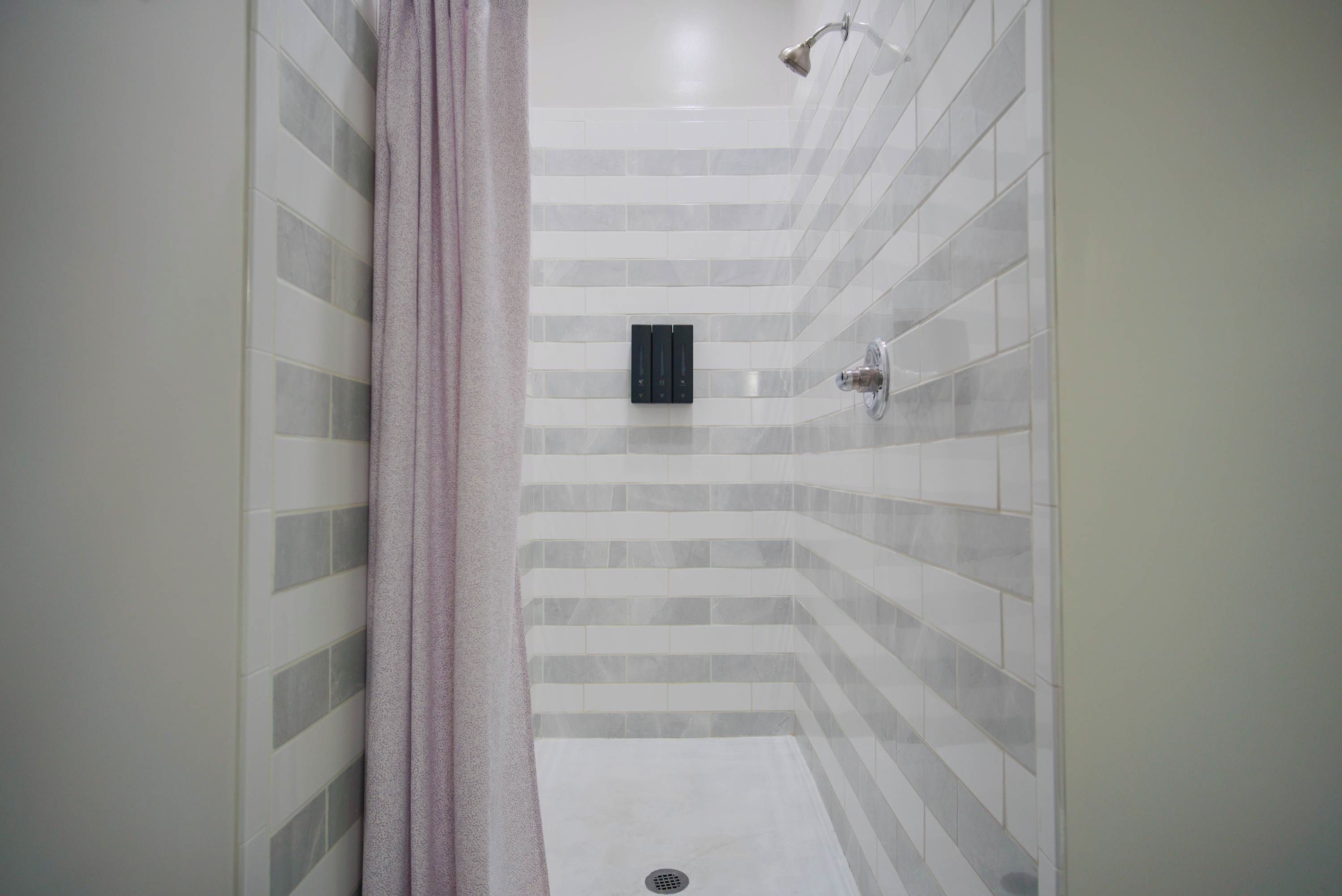 A shower area with a tiled wall, a showerhead, and a drain.