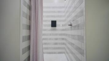 A shower area with a tiled wall, a showerhead, and a drain.