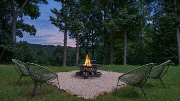 An outdoor seating area with a fire pit, surrounded by a gravel circle, and two chairs facing the fire.