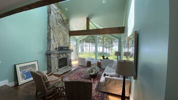 A spacious living room with a stone fireplace, large windows, and a cozy seating area.