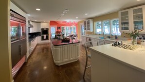 Une cuisine moderne avec des meubles blancs, un îlot central et un coin repas avec des chaises.
